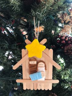 a wooden ornament with a nativity scene hanging on a christmas tree branch