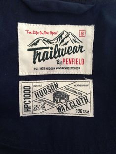 two patches on the back of a black jacket that says trailwear by penfield