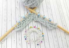 two crocheted knitting needles with yarn and beads on them sitting next to each other