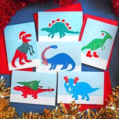 six dinosaur cards with red, green and blue designs on them are surrounded by tinsel