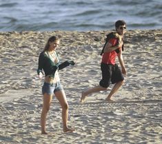 two people are running on the beach together