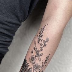 a woman's arm with flowers and leaves tattooed on the left side of her arm