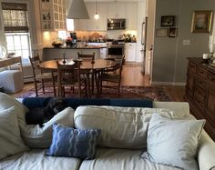 a living room filled with furniture next to a kitchen and dining room table in the background