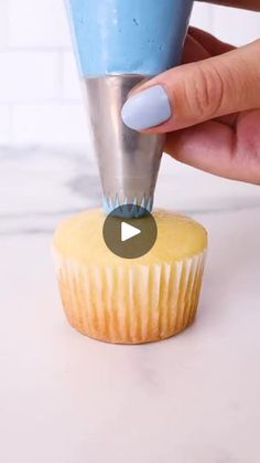 a cupcake being held by a person with blue fingernails