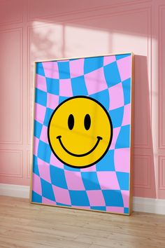 a smiley face painted on a pink and blue checkered canvas in an empty room