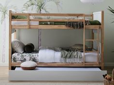 a bunk bed with two sets of pillows and blankets on top of the bottom bunk