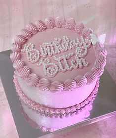 a pink birthday cake sitting on top of a glass plate with the words happy bling