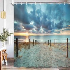 a shower curtain with a sunset on the beach and clouds in the sky above it