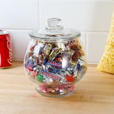 a glass jar filled with candy sitting on top of a counter next to a can