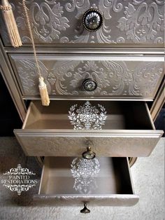 an ornate silver dresser with two drawers and tassels on the drawer pulls,