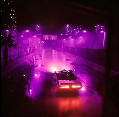 a car driving down a street at night in the rain with purple lights on it