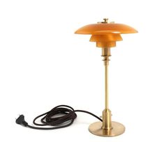 an orange table lamp with a black cord plugged into the base and one light on top