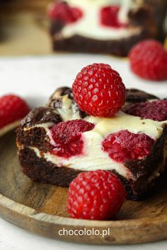 a piece of chocolate cake with raspberries on top is sitting on a wooden plate