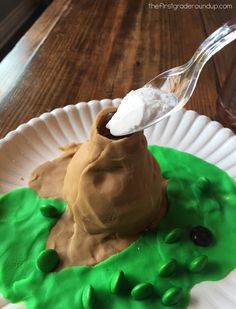 a paper plate that has some kind of pudding on it with green icing and a spoon in it