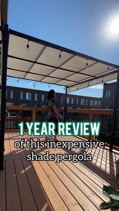 a person on a wooden deck under a white awning with the words 1 year review of this expensive shade pergola