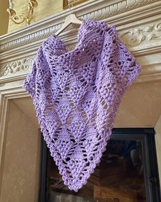 a purple crocheted shawl hanging from a fireplace mantel