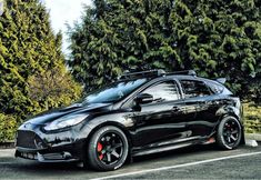 a black car parked in front of some trees