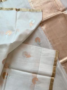 An exquisite pure 100% silk organza/kora benarasi saree in off white with copper & silver alfi buta (floral motif) woven throughout the six yards, along with a sleek golden border on either side. This saree is very stylish and classy, especially because of its simplicity and grace. The alfi (technique in Benaras weaving using two colored yarns) buta looks so stunning with the silver and copper zari as it keeps alternating with each motif. The pallu has a solid copper zari weaving. The fabric White Cotton Silk Traditional Wear For Festive Season, White Cotton Silk Dupatta For Wedding, Festive Off White Organza Saree, Festive Off-white Organza Saree, White Traditional Wear With Sheer Dupatta In Tissue Silk, Elegant White Tissue Silk Traditional Wear, Elegant White Silk Traditional Wear, White Silk Traditional Wear For Eid, Festive White Chanderi Saree