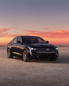 a black cadillac parked in the middle of a desert at sunset with clouds above it