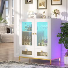 a white cabinet with glass doors in a living room next to a potted plant