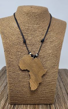 a wooden africa map necklace on a mannequin neckle with beads and black cord