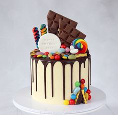 a birthday cake decorated with candy, candies and chocolate on a white platter