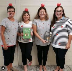 three women in striped shirts holding books with apples on their heads and standing next to each other