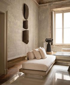 a large white couch sitting in a living room next to a window and vase on top of a table