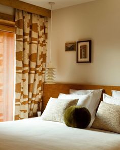 a bed with white sheets and pillows next to a window