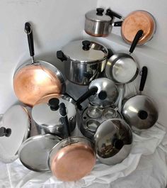 a pile of pots and pans sitting on top of a white cloth covered table