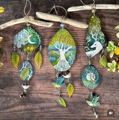 several handmade ceramic ornaments hanging on a tree branch with flowers and leaves around them