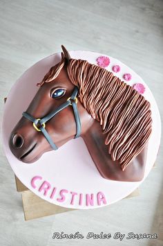 there is a horse cake on top of the wooden table and it says cristina