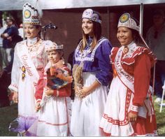 four women in costumes posing for a photo with one holding a small child and the other wearing a tiara