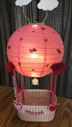 a hot air balloon in a basket with hearts on it and two clouds above it