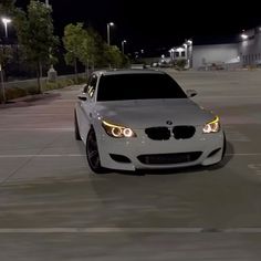 a white car is parked in a parking lot at night with its lights turned on