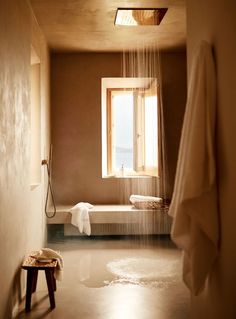 a bath room with a shower head next to a window and a bench in front of it