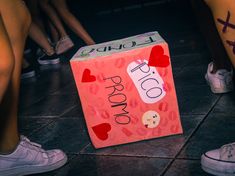 a box that is sitting on the ground with hearts painted on it and people standing around