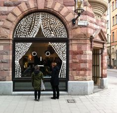 two people standing in front of a store window