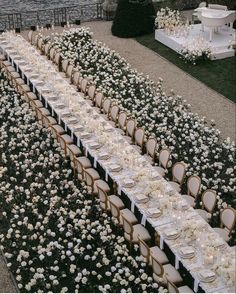 a long table is set with white flowers and place settings for an outdoor wedding reception