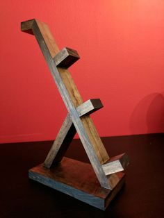 a wooden sculpture sitting on top of a table next to a red wall with a cross painted on it