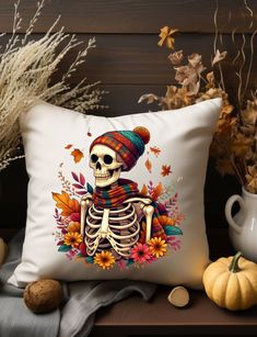 a pillow that has a skeleton on it with autumn leaves around it and pumpkins in the background