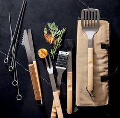 various kitchen utensils are laid out on a black surface, including knives and spatulas