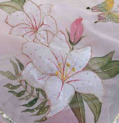 a white flower with green leaves on a pink table cloth and some butterflies in the background