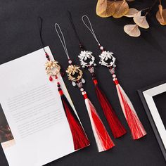 five tasseled earrings on top of a table next to an open book and framed photograph