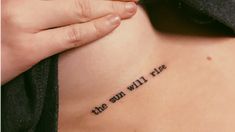 a woman with a tattoo saying the sun will rise on her stomach and behind her back