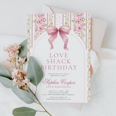 a pink and white birthday card with flowers on it, next to some green leaves