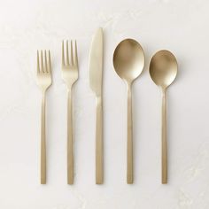 gold flatware is laid out on a white surface