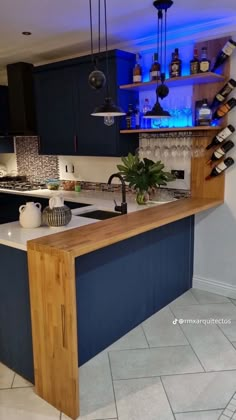 a kitchen with blue cabinets and an island counter top in the center, surrounded by wine bottles