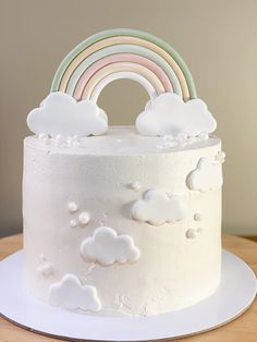 there is a white cake with clouds and a rainbow on it