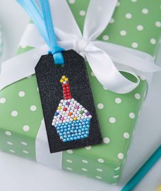 a gift wrapped in green and white polka dot paper with a birthday cupcake ornament on it